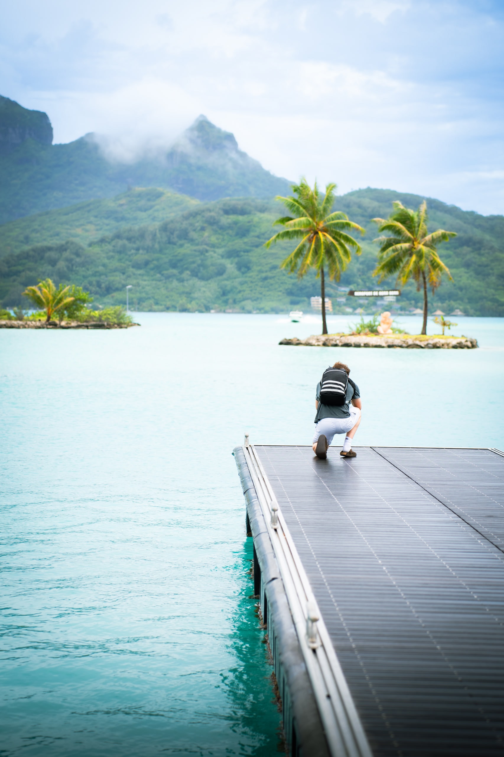 A small palm island and jetty across shallow water