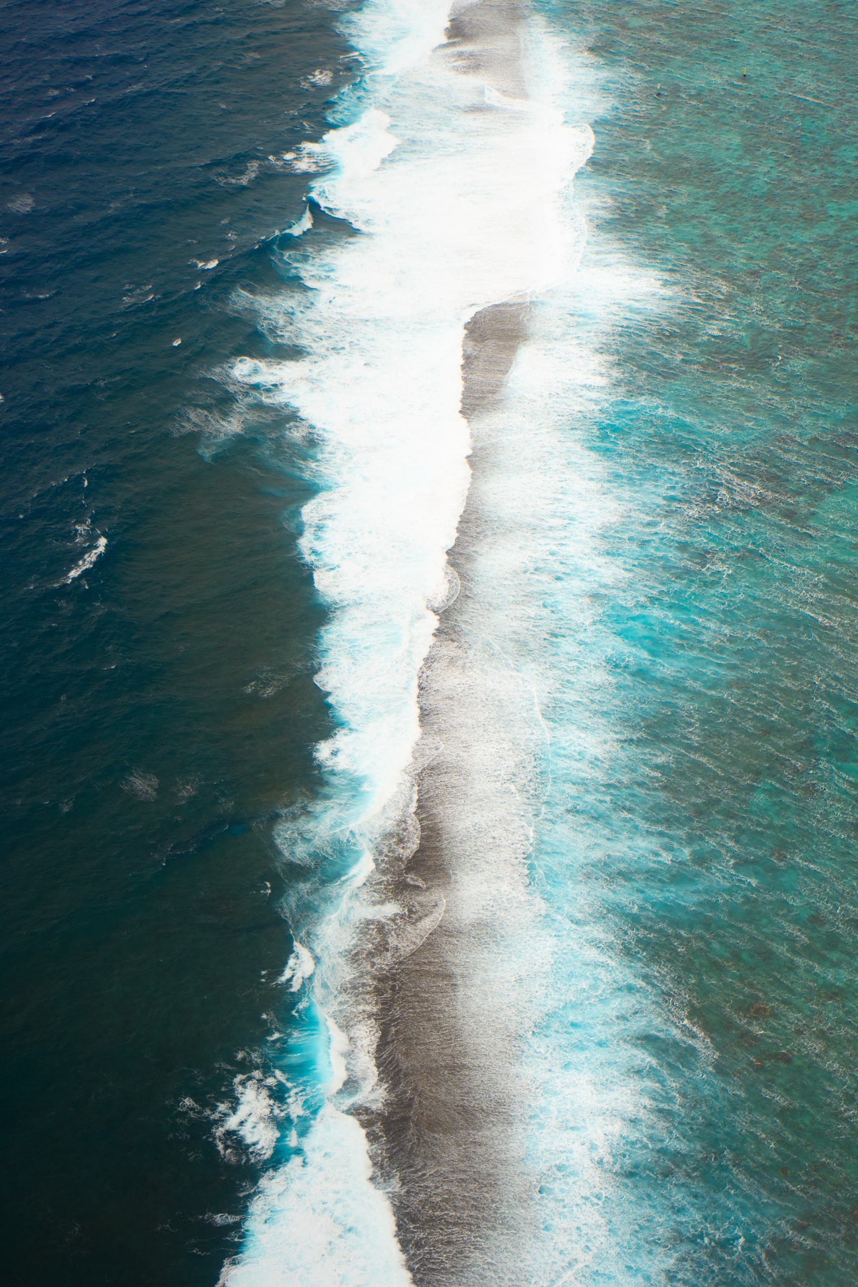 Surf breaking along the edge of a reef, seen from the air