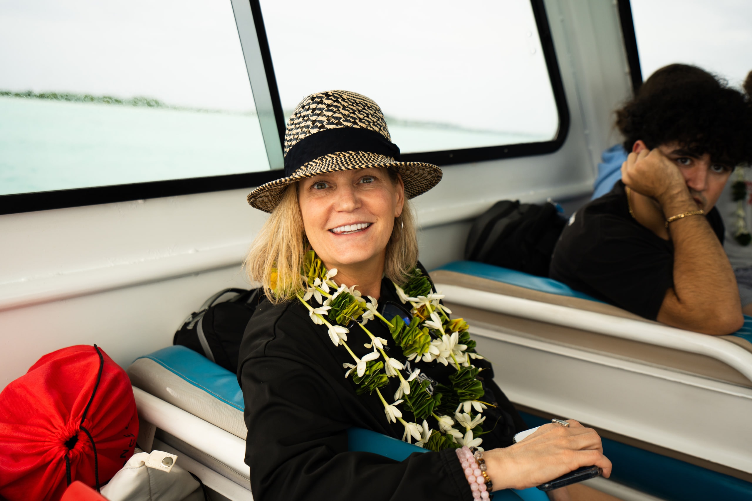 A woman wearing a flower lei seated by a boat window