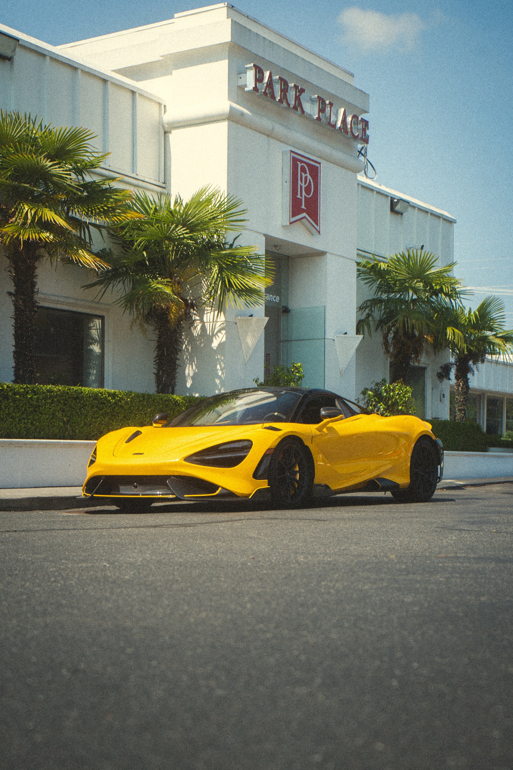 A yellow sports car parked outside a low white building