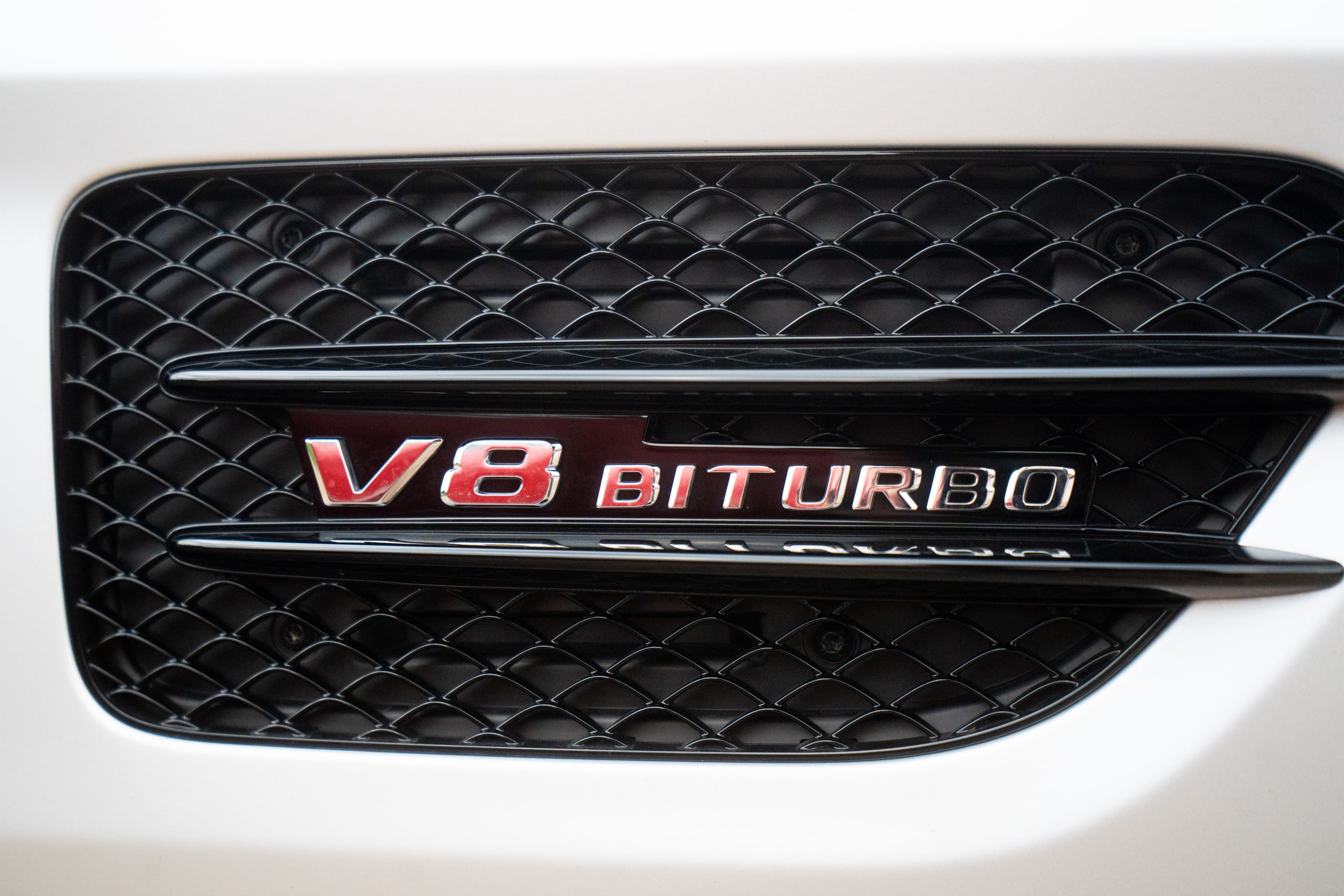 A V8 Biturbo badge on the front wing of a white car