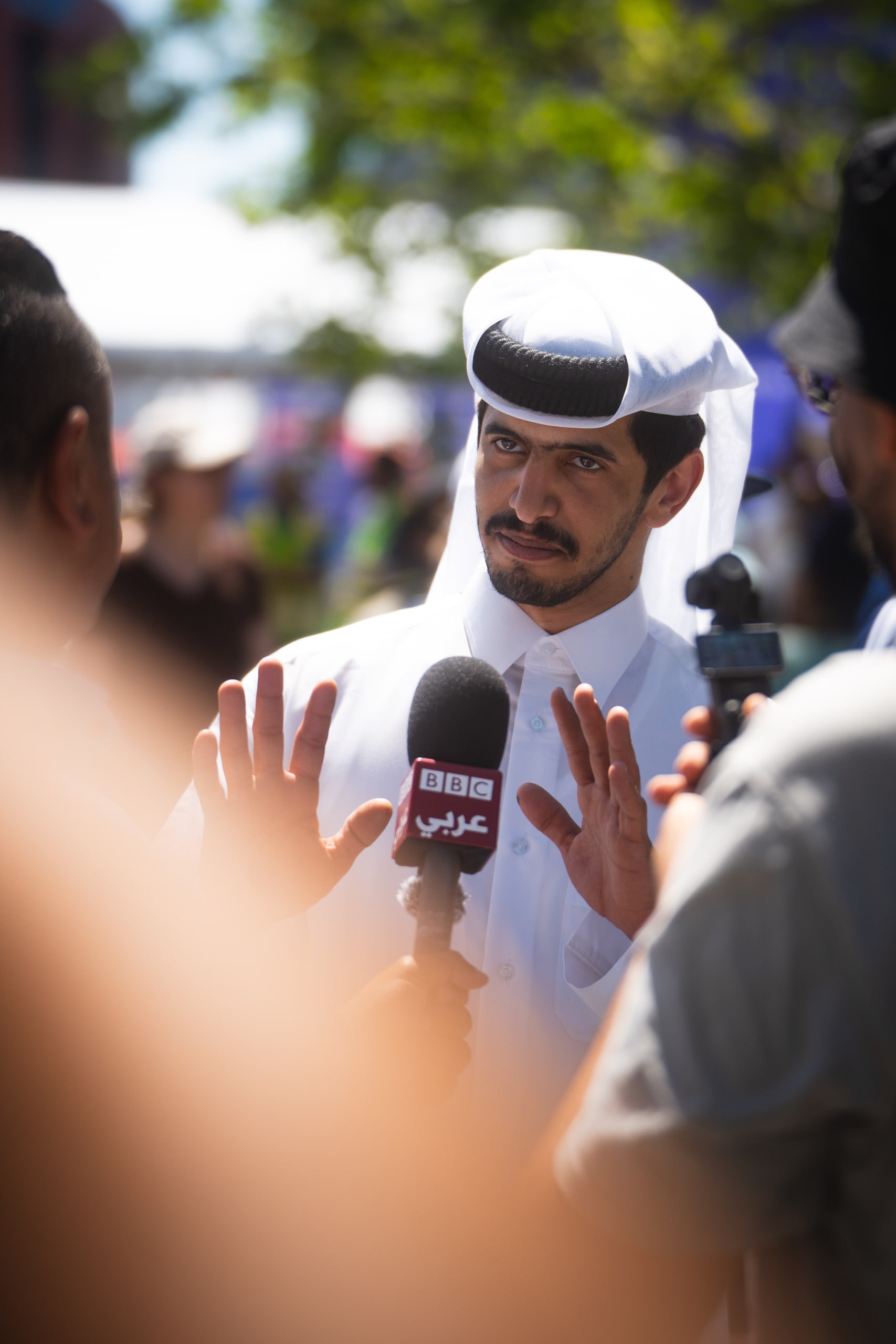 A man in a white headdress speaking into a microphone in a crowd