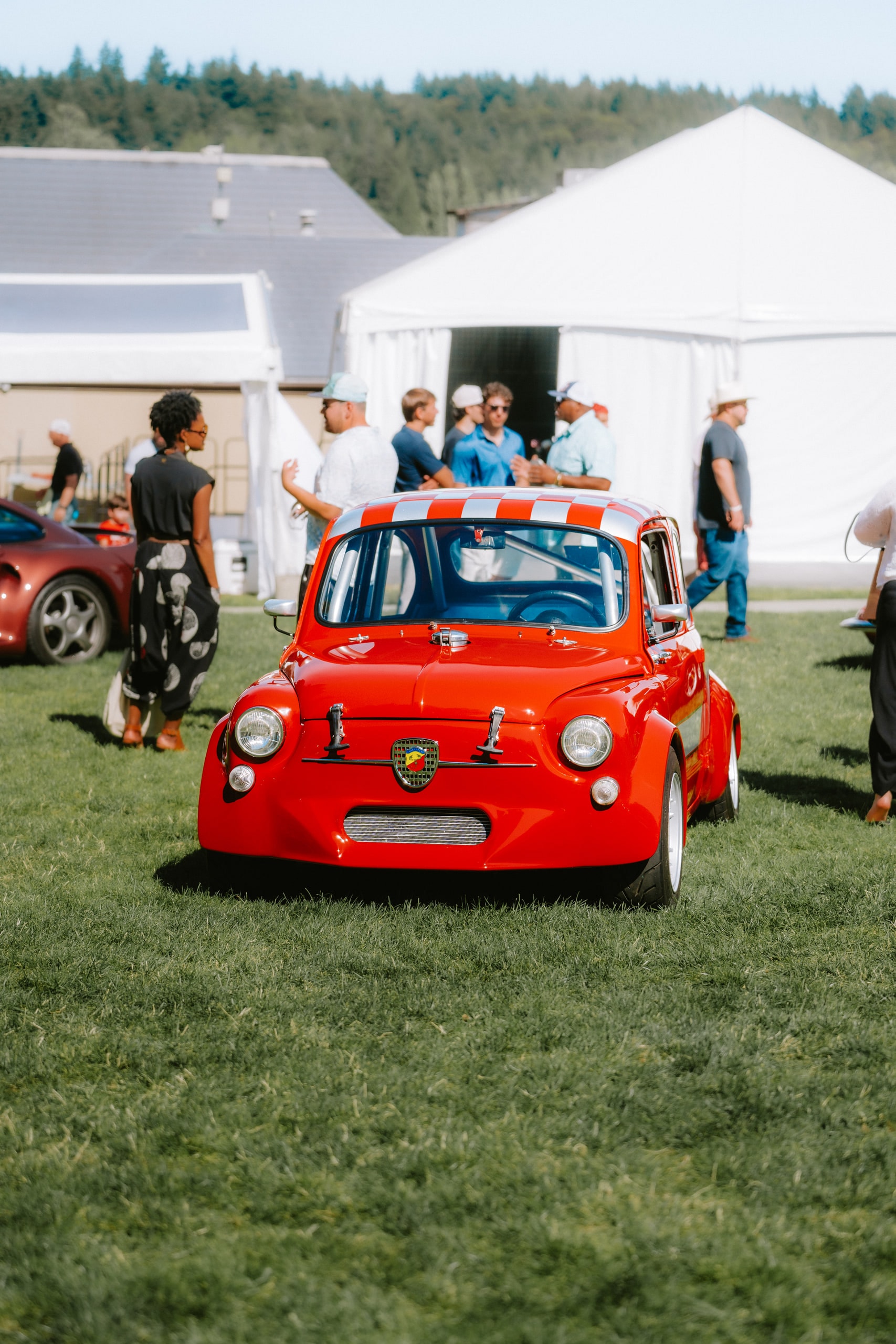 A small red car with its bonnet raised at a show