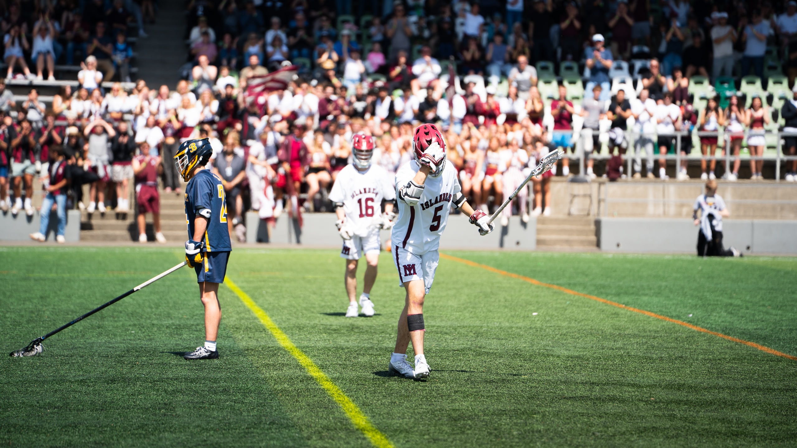 Two lacrosse teams facing off in front of a full stand