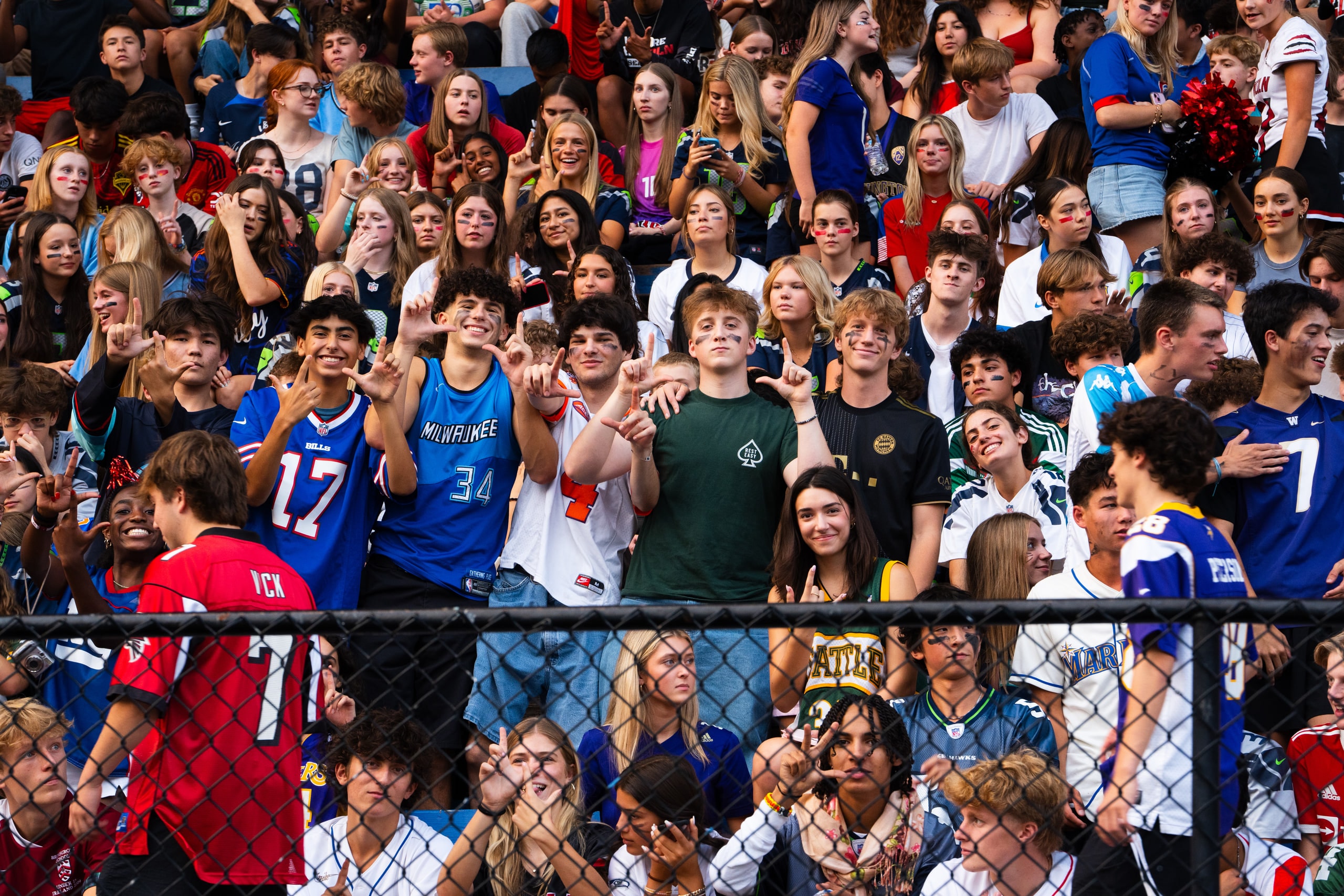 Students pressed against the fence at the front of the stands